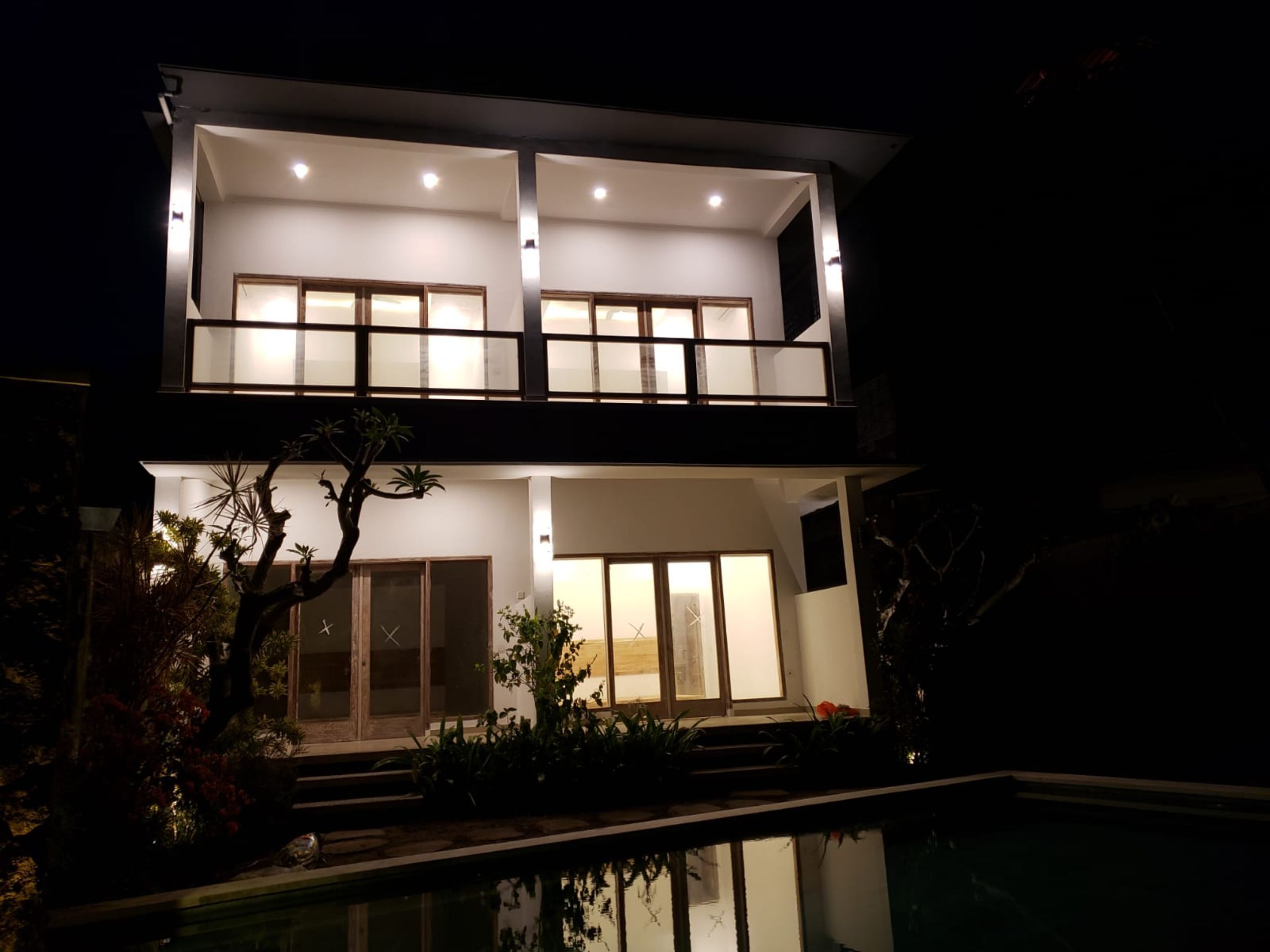 Une maison à deux étages avec une piscine en premier plan.