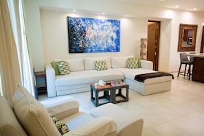 A living room with a sofa, a coffee table, and a large abstract painting on the wall. - Gorgeous 1 Bedroom Unit at V399, amazing Rooftop 1BD Condo for rent in Old Town, (Puerto Vallarta)