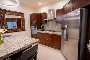 A kitchen with granite countertops, stainless steel appliances, wooden cabinets, and a decorative mirror.