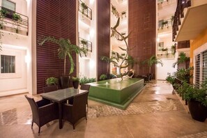 Relax in a serene indoor oasis surrounded by lush greenery and a tranquil water feature.