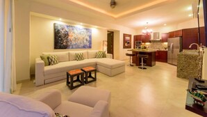 A modern living room with a sectional sofa, a coffee table, and a kitchen area with a granite countertop and stainless steel appliances. - Gorgeous 1 Bedroom Unit at V399, amazing Rooftop 1BD Condo for rent in Old Town, (Puerto Vallarta)