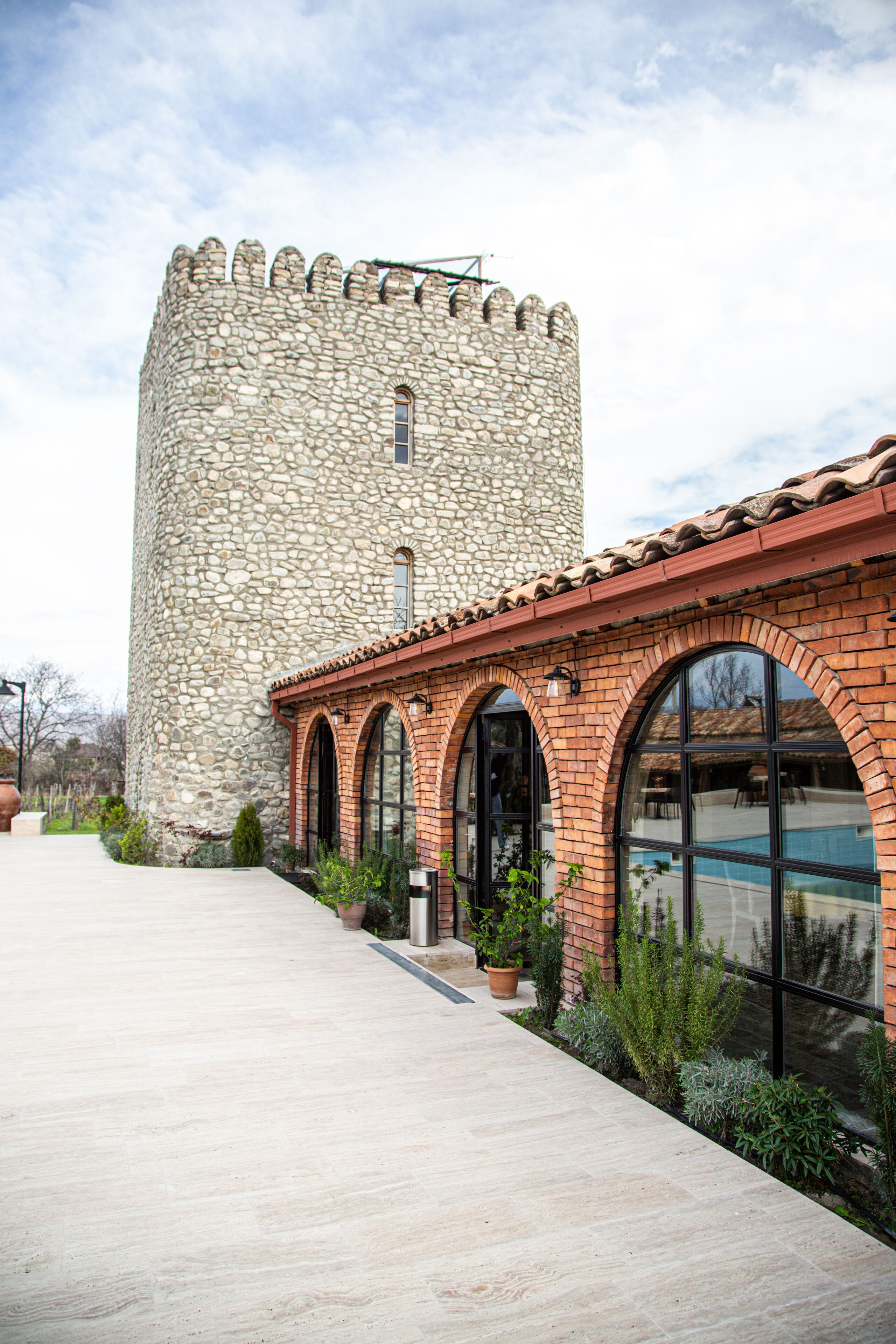 A stone tower with a brick building in front.