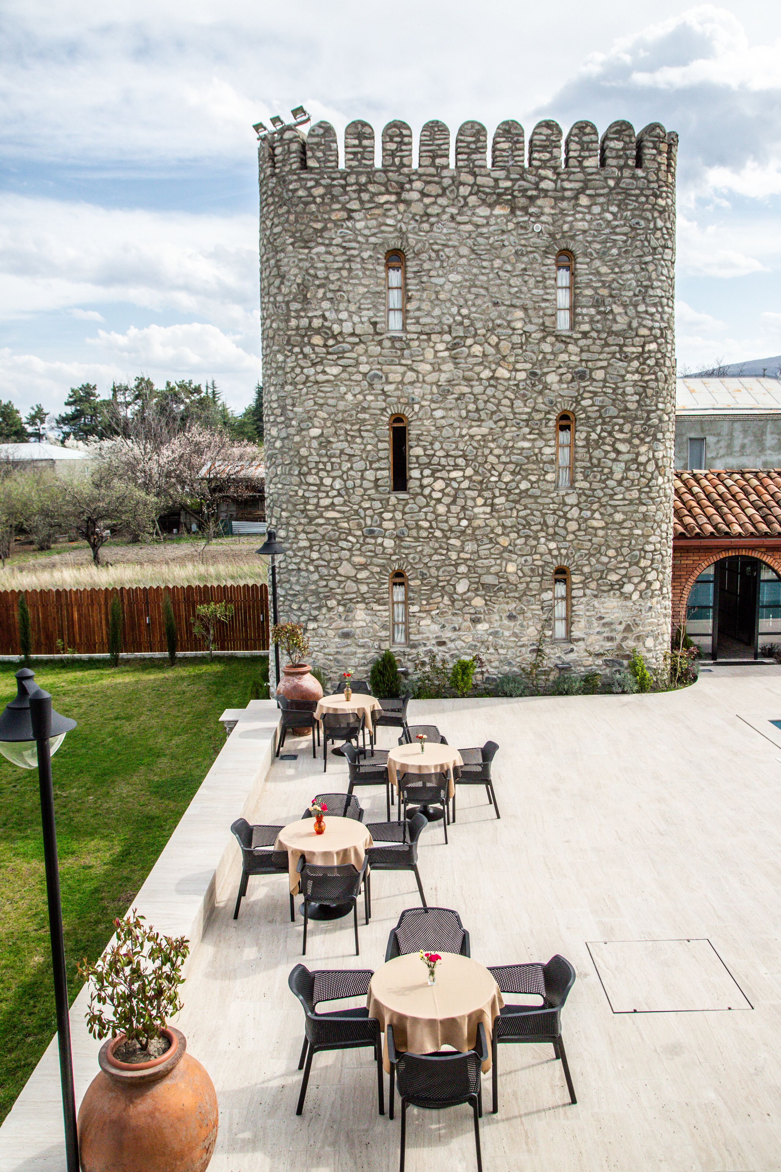 A stone castle with a courtyard featuring outdoor seating and a large vase.