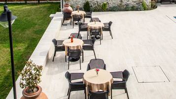 A stone castle with a courtyard featuring outdoor seating and a large vase.