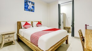 Un dormitorio ordenado con una cama de madera, una mesita de noche pequeña, un espejo y una silla de madera.