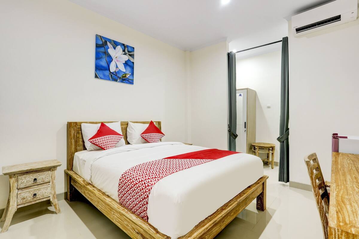 Ein ordentlich eingerichtetes Schlafzimmer mit einem hölzernen Bett, einem kleinen Nachttisch, einem Spiegel und einem Holzstuhl.