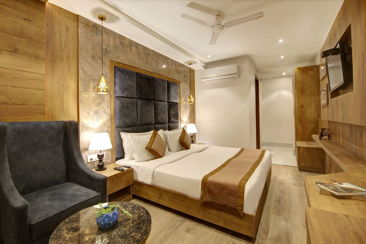 A hotel room with a bed, a chair, a table, and a TV.