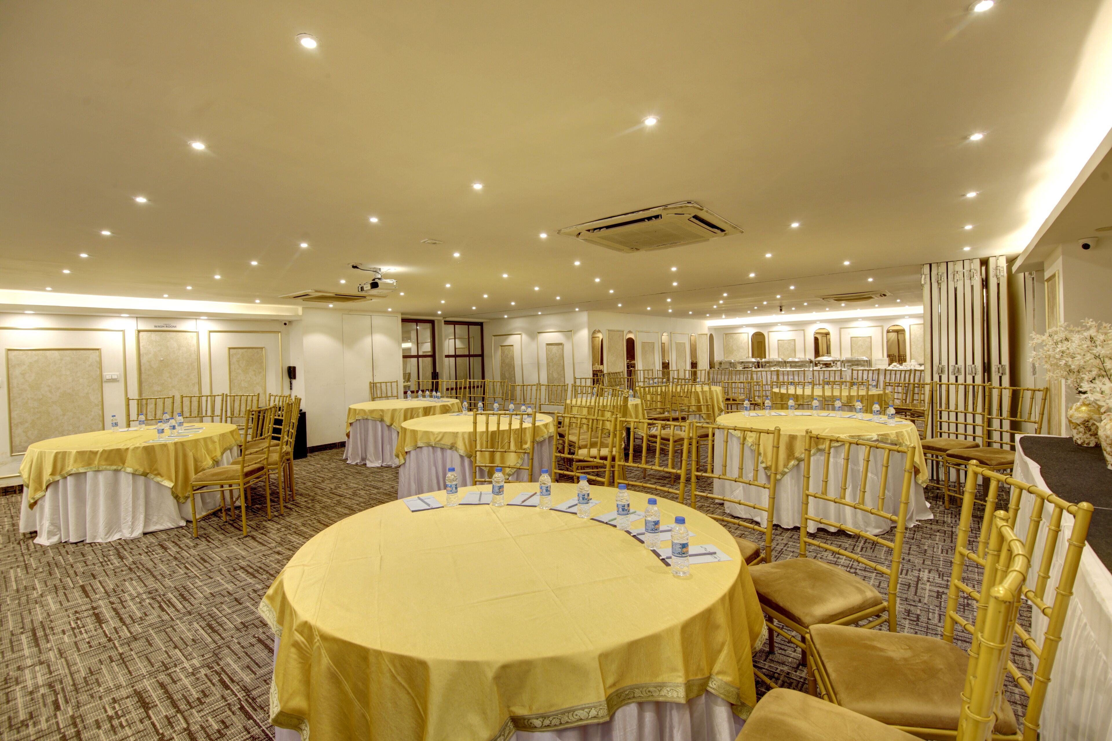 A banquet hall with round tables, chairs, and a carpeted floor.