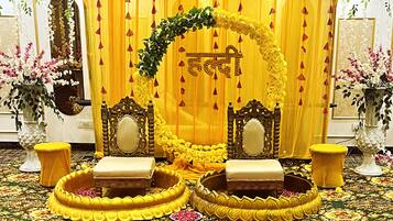 A stage with yellow curtains and floral decorations, two chairs, and a projector.