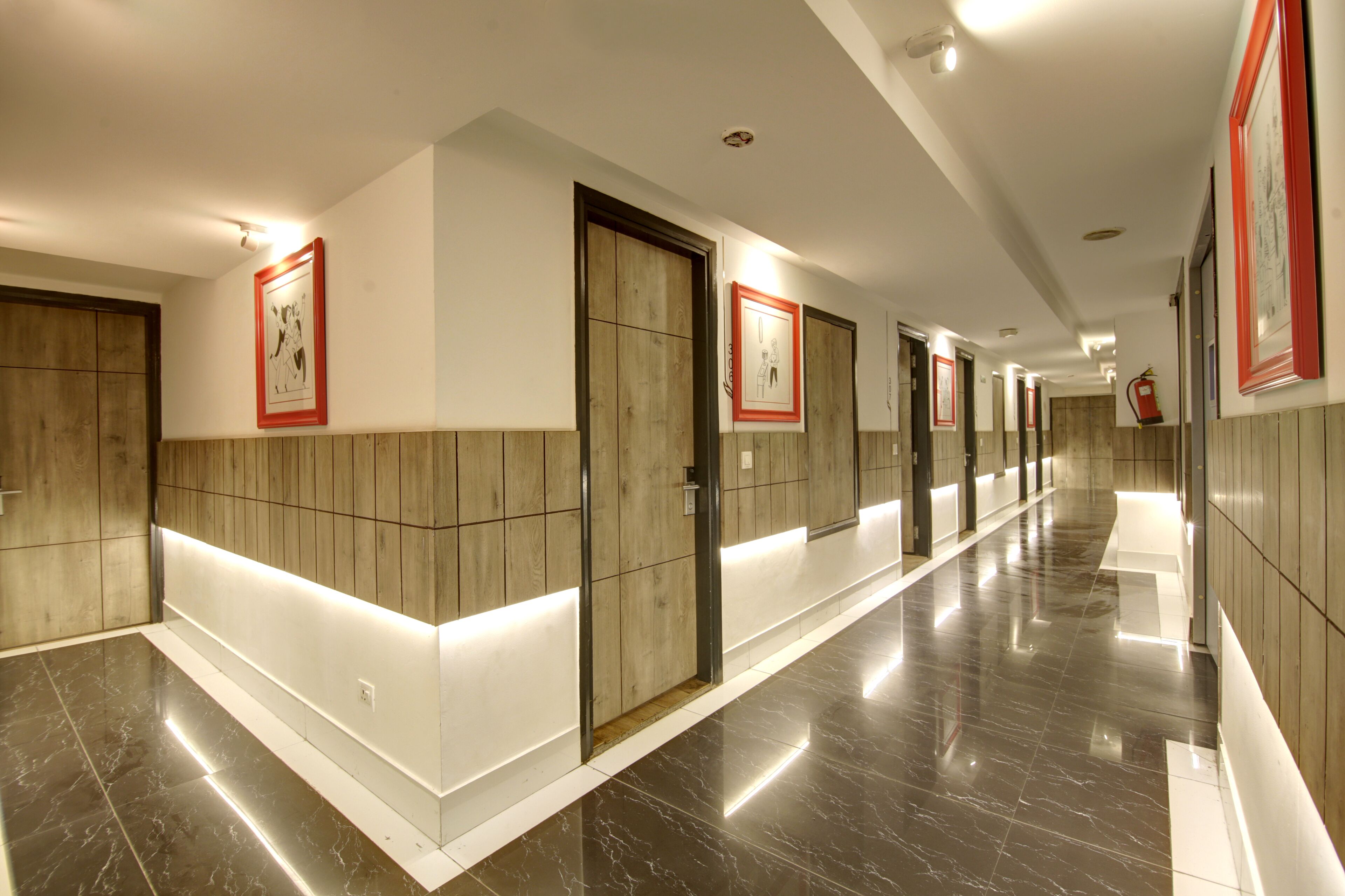 A long, well-lit hallway with wooden paneling and framed artwork on the walls.