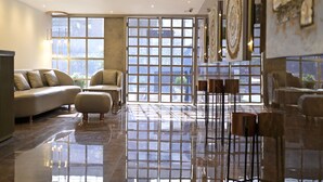 A spacious lobby with a large window, a sofa, and a coffee table. - Town Pallace Inn (New Delhi)