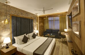 A hotel room with a bed, a sofa, a desk, and a bicycle. - Town Pallace Inn (New Delhi)