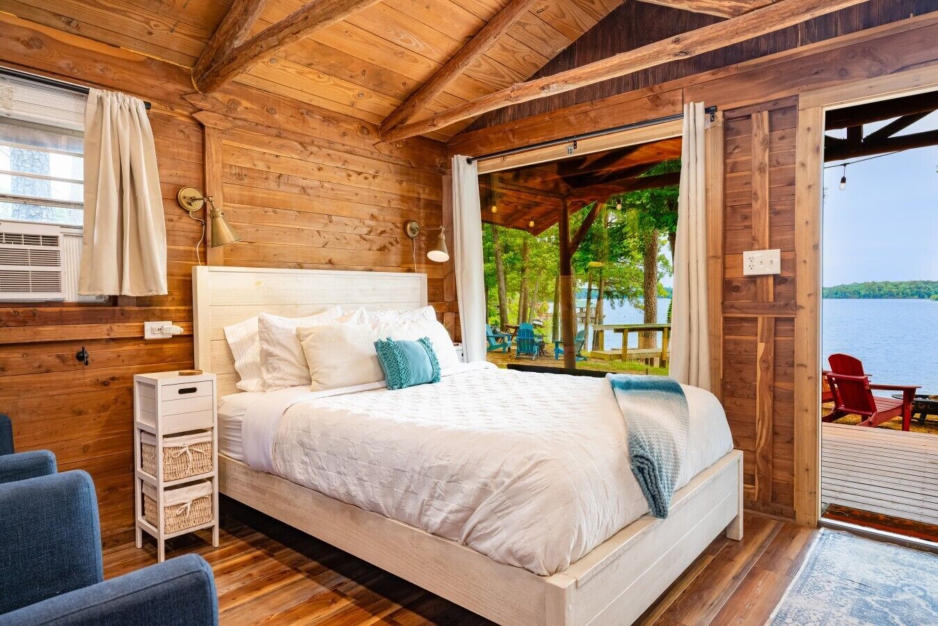 A wooden cabin room with a bed, a small table, and a chair.