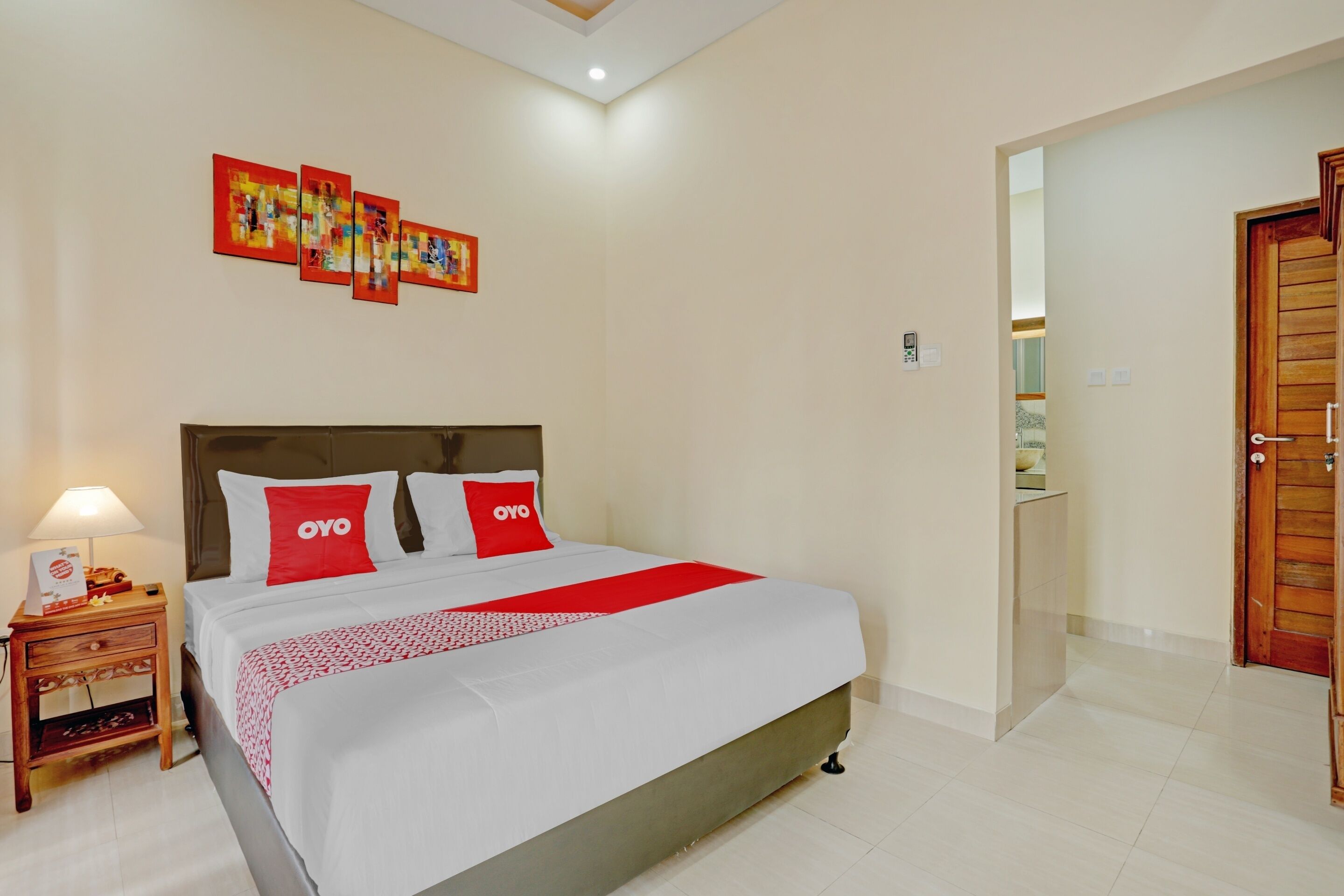 Habitación de hotel impecable con una cama grande, una mesita de noche con lámpara y una puerta de madera.