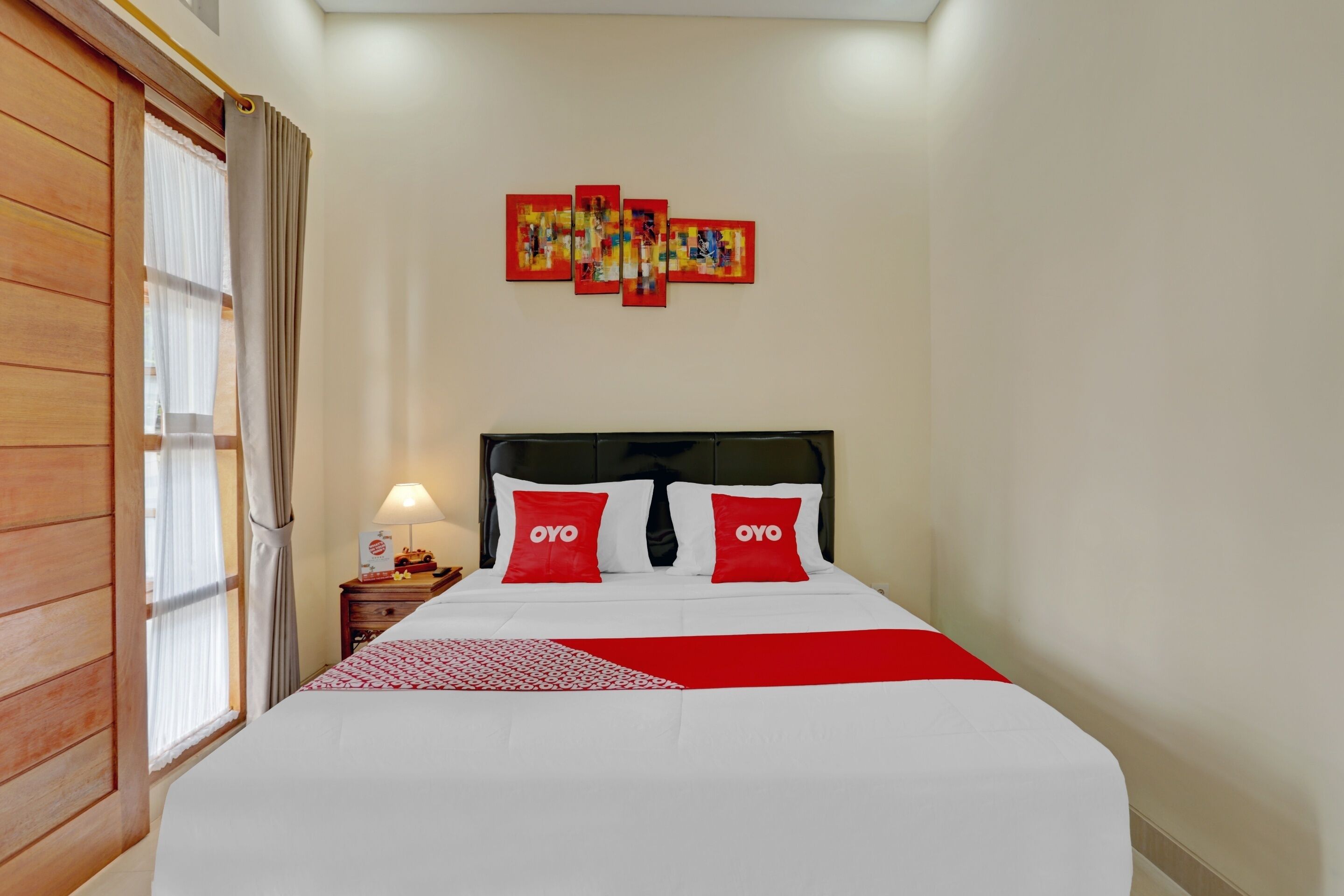Quarto de hotel com uma cama, mesa de cabeceira, abajur e janela com cortinas.
