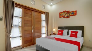 Ein Hotelzimmer mit einem großen Bett, einem Holzschrank, einem Nachttisch mit Lampe und drei an der Wand hängenden Bildern.