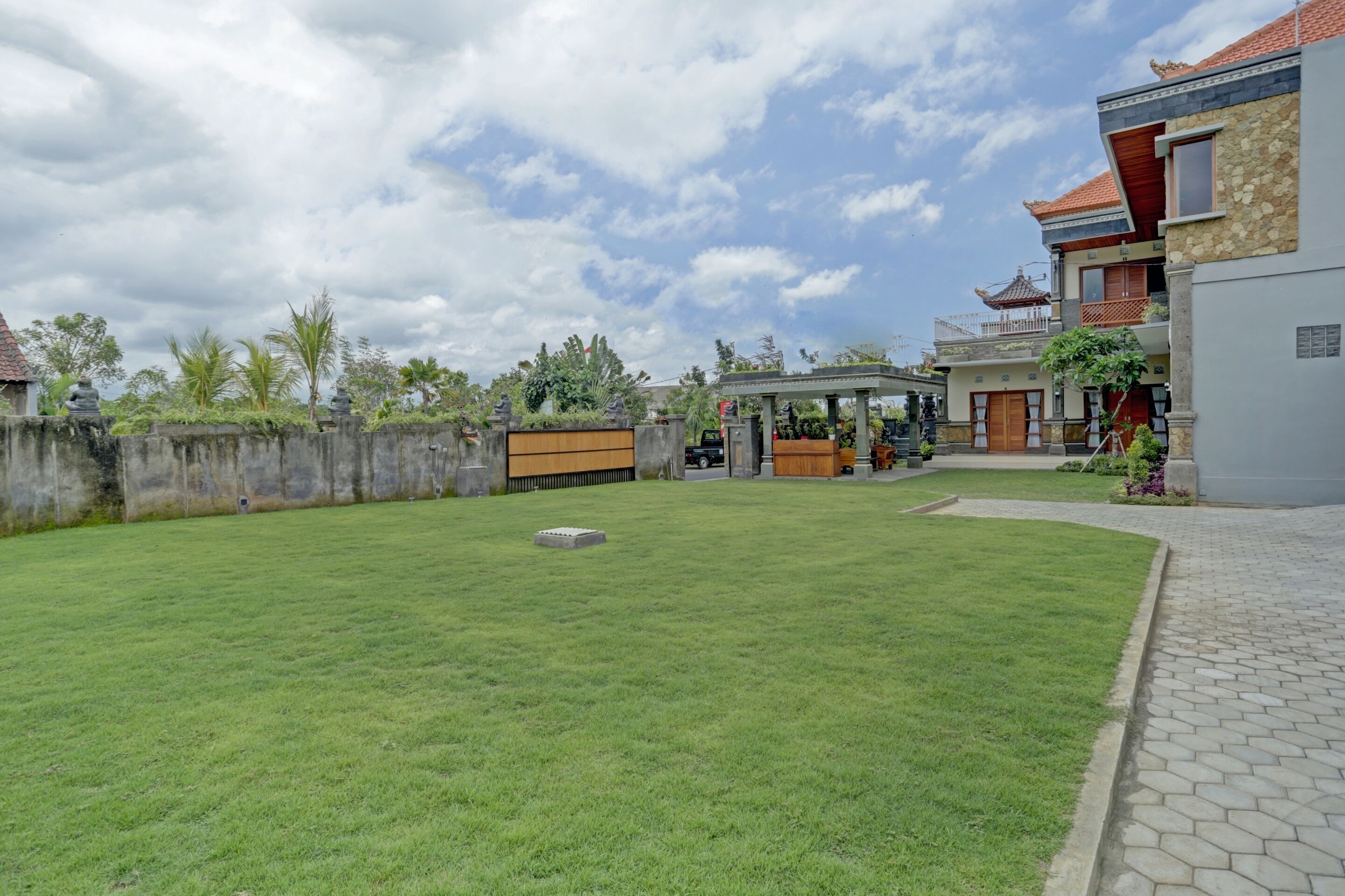 Um gramado bem cuidado, um gazebo e um edifício com telhado de cerâmica e fachada de pedra.