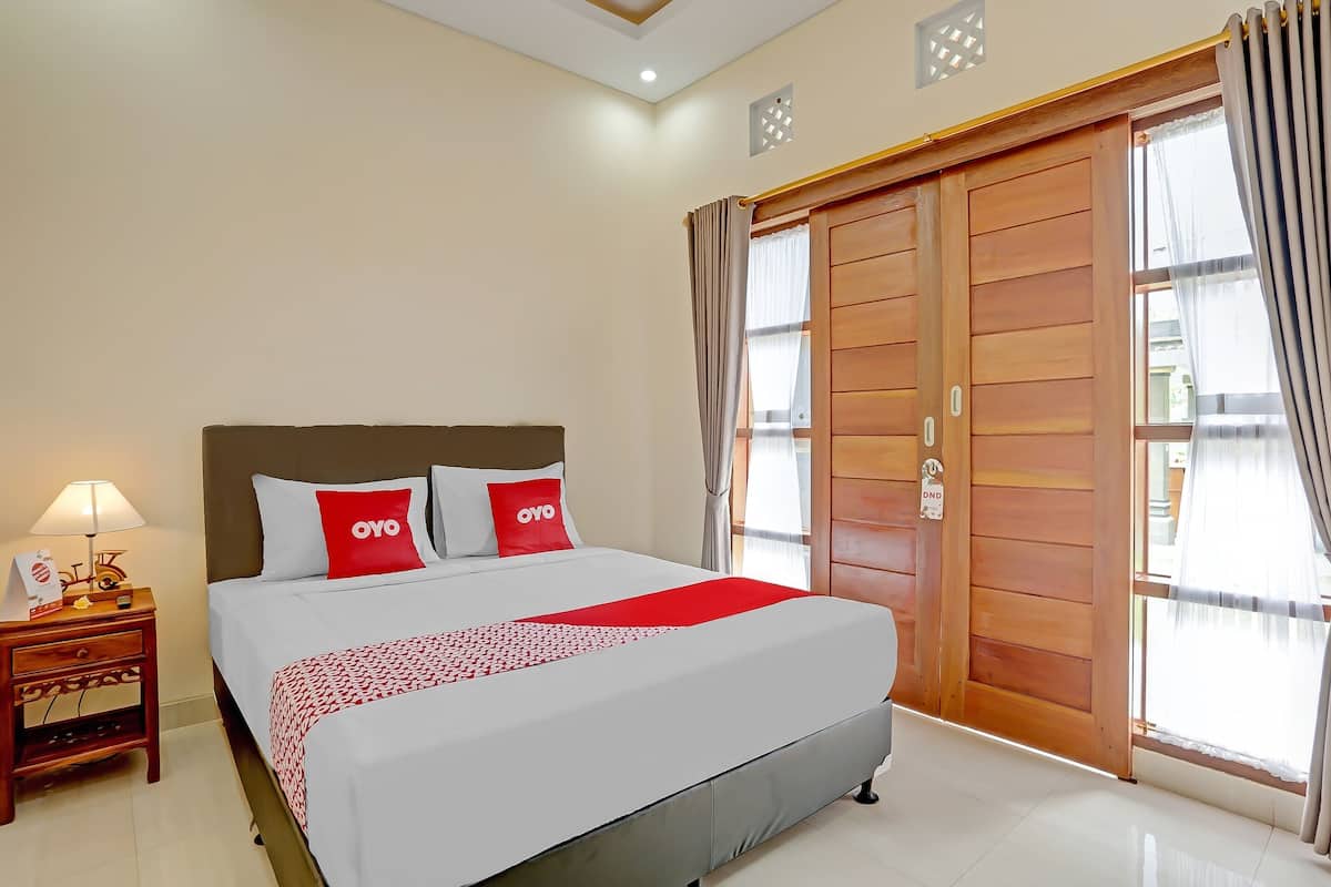 Ein Hotelzimmer mit einem großen Bett, einem Nachttisch mit Lampe und einem Holzschrank.