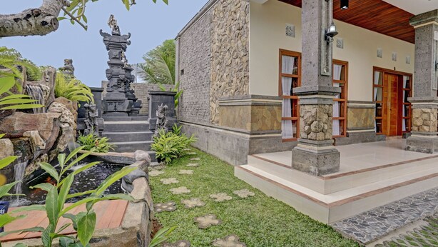 Ein traditionelles Gebäude mit einer Steinfassade, einem kleinen Wasserfall und einem gepflegten Garten mit trittfesten Steinplatten.
