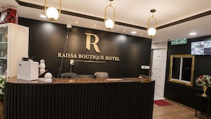 A reception desk with a black and gold design, a sign reading 'RAISSA BOUTIQUE HOTEL,' and a 'KELUAR' sign indicating the exit. - Raissa Boutique Hotel (Kuala Lumpur)
