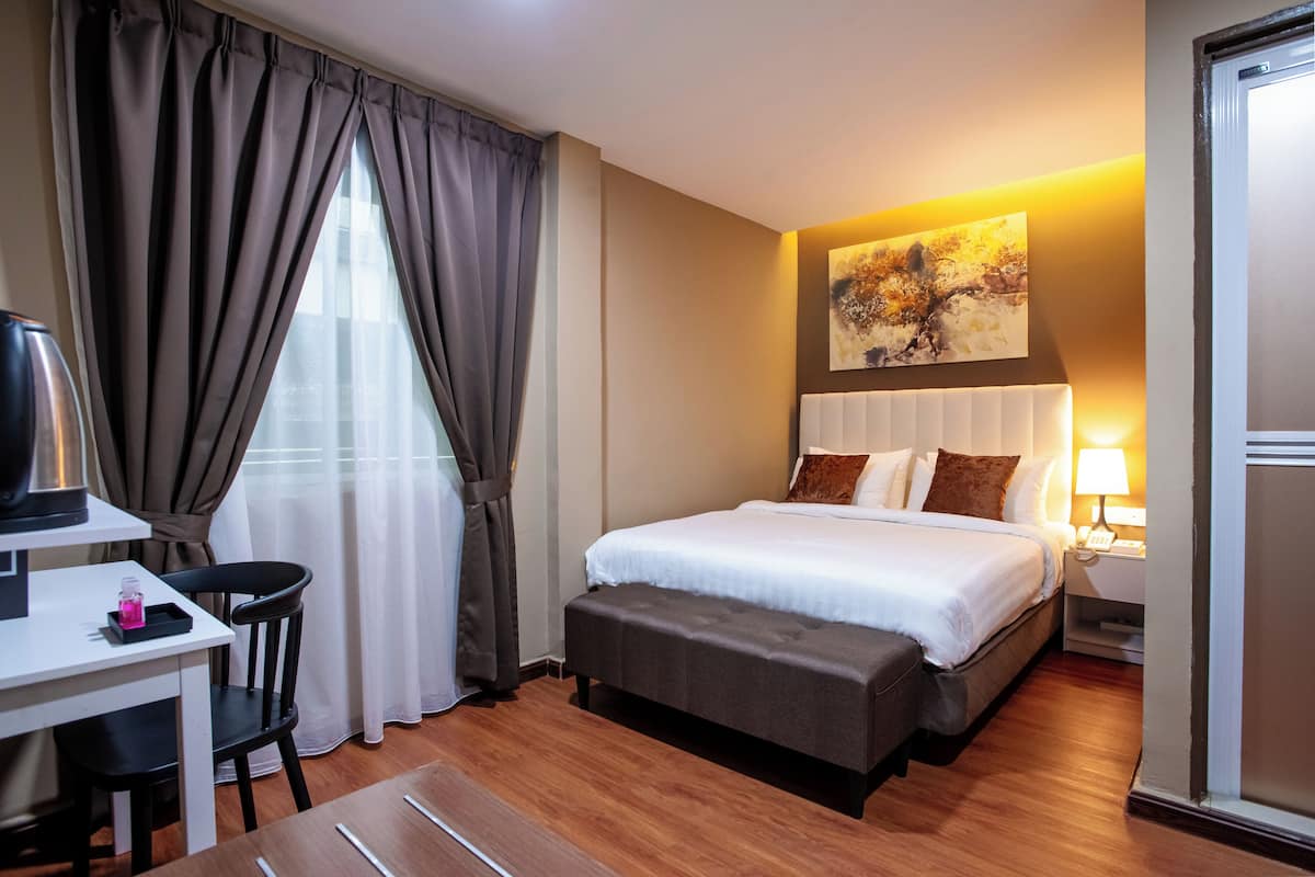 Una habitación de hotel con cama, mesita de noche, lámpara y un cuadro en la pared.