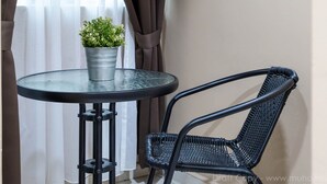 A small round table with a potted plant, a black wicker chair, and a window with curtains. - Raissa Boutique Hotel (Kuala Lumpur)