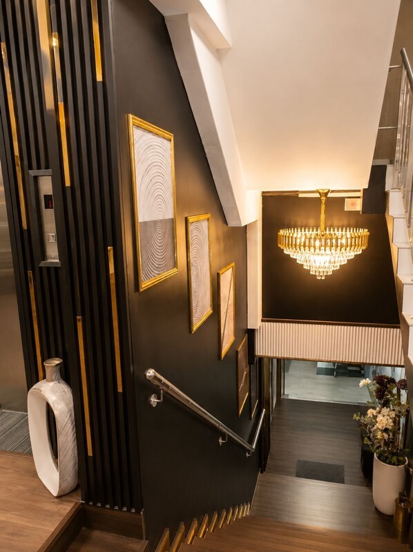 A modern interior with a staircase, a chandelier, and framed artwork on the walls.