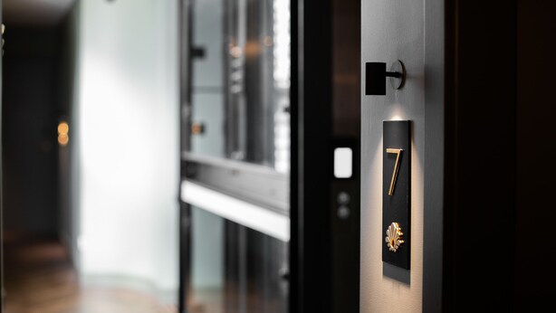 A modern hallway with a door labeled '7' and a decorative emblem. - The Sarah by Urban Rest (Darlinghurst)
