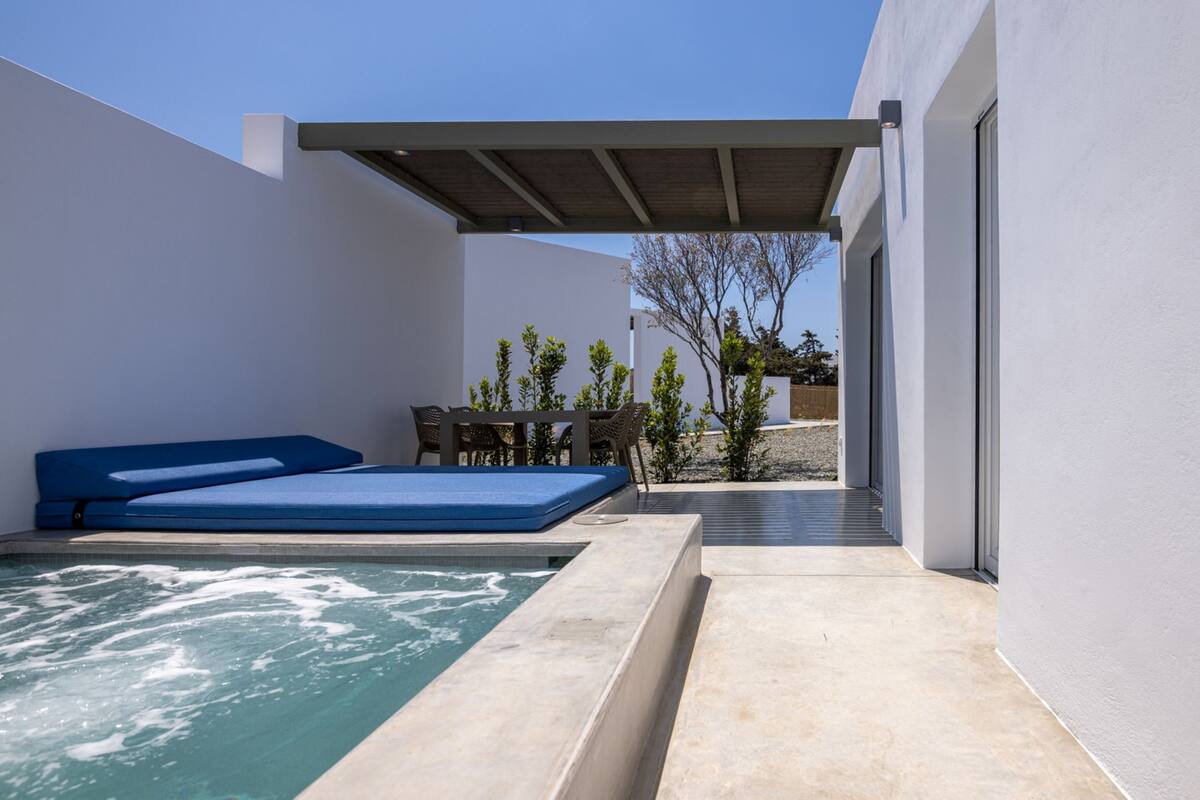 A modern outdoor pool area with a blue lounge chair, a small table, and a pergola.
