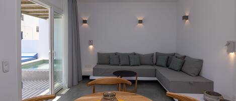 A modern living room with a sofa, a round wooden table, and a glass vase.