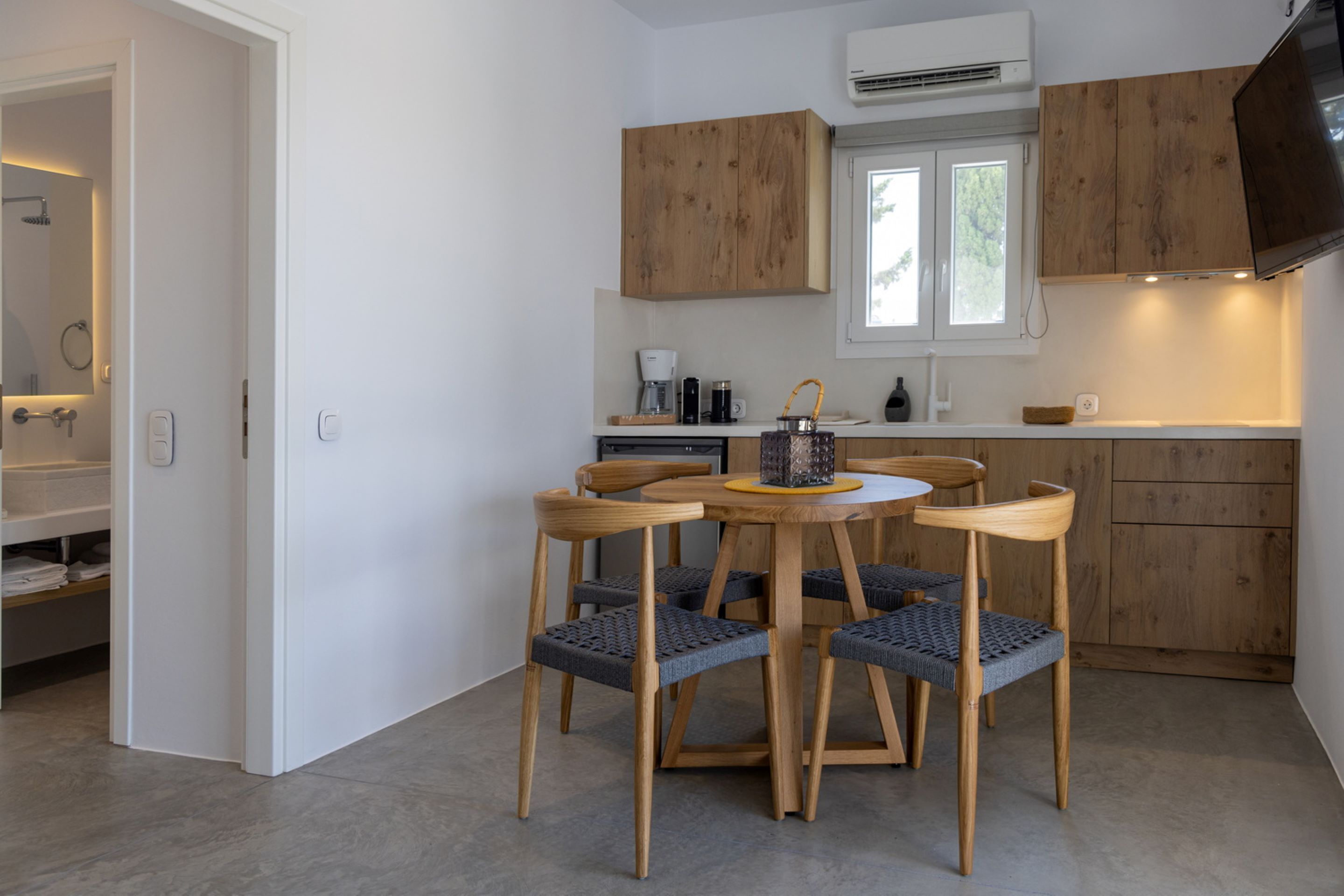 A modern kitchen with wooden cabinets, a dining table with chairs, and a window.