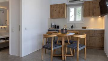 A modern kitchen with wooden cabinets, a dining table with chairs, and a window.