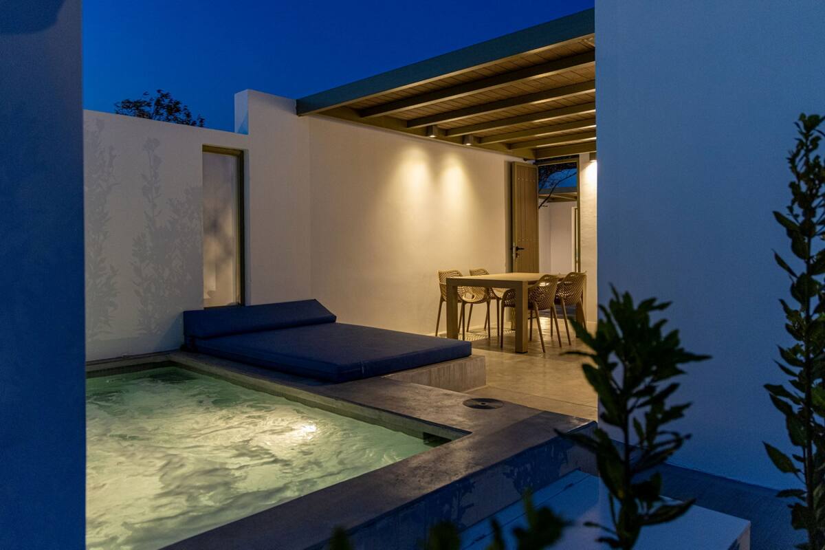 A modern outdoor pool area with a hot tub, seating, and a dining area.
