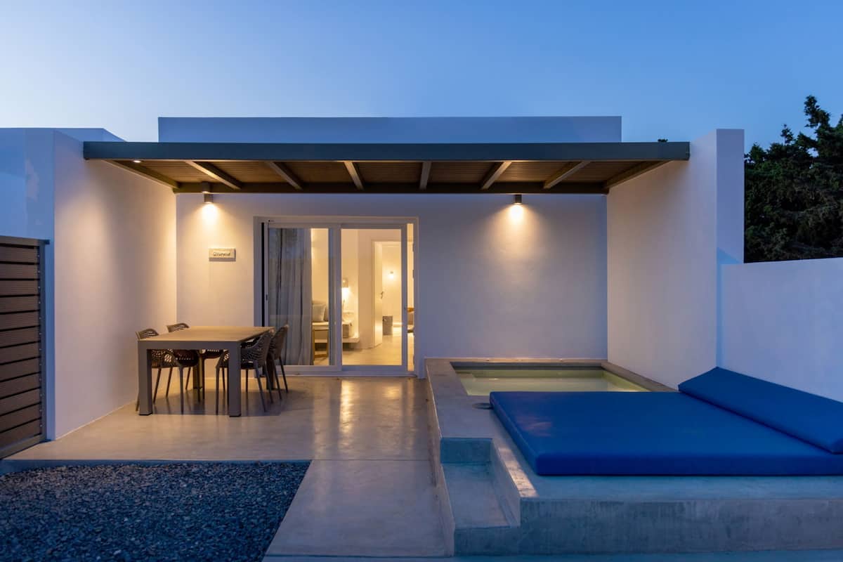 A modern outdoor patio with a dining table and chairs, a blue cushioned seating area, and a small pool.