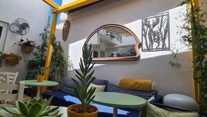 Et udendørs siddeområde med et rundt bord, en sofa og plantekasser.