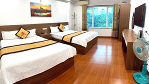 Quarto de hotel com duas camas, televisão, ventilador e uma janela grande com vista.