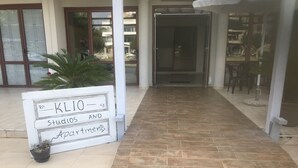 Un letrero que indica 'KL10 - Estudios y Apartamentos' con un sendero empedrado que lleva a la entrada del edificio.