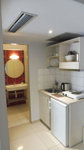 A compact kitchen with a sink, stove, and a small refrigerator. - Klio Apartments and Studios (Dio-Olympos)