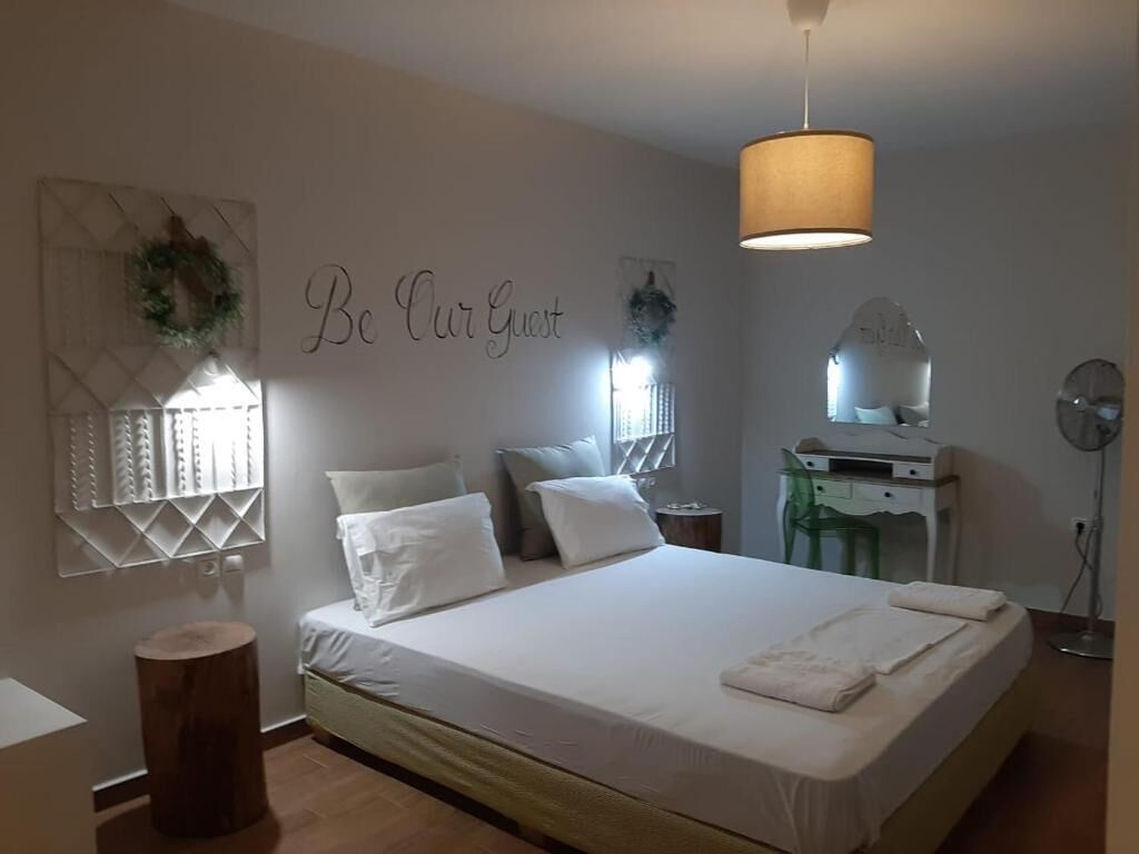 Un dormitorio con una cama, un letrero en la pared, un espejo, un escritorio y un ventilador de pie.