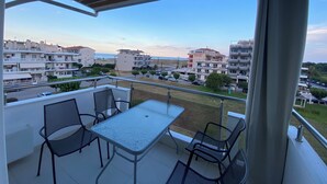Un balcón con una mesa y sillas, con vista a un barrio residencial con edificios y una calle.