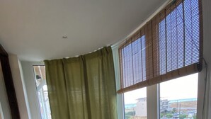 Una habitación con un sofá amarillo, una mesa blanca y vistas a una zona residencial a través de amplios ventanales.