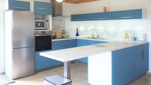 Una cucina moderna con mobili blu, un frigorifero in acciaio inossidabile, un forno a microonde e una macchina da caffè.