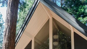 A modern house with a large porch, two chairs, and a tree nearby. - Nevada City Cabin Pups and Long Stays Welcome (Nevada City)