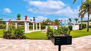 A garden area with a gazebo, palm trees, and a barbecue grill. - Cottage Home by Beaches, Golf & More! Heated Pool! (Fort Myers)