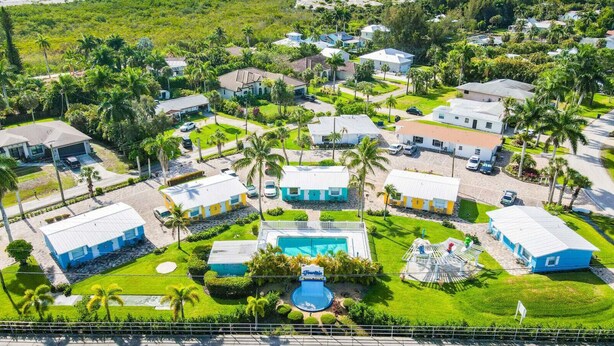 An aerial view of a residential area with houses, a swimming pool, and palm trees. - Cottage Home by Beaches, Golf & More! Heated Pool! (Fort Myers)