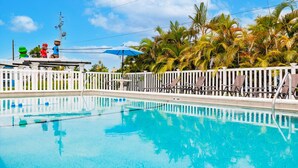 A swimming pool with lounge chairs and a white fence. - Cottage Home by Beaches, Golf & More! Heated Pool! (Fort Myers)