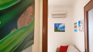 Ein Flur mit einem Kindergemälde, einer Klimaanlage und drei kleinen Landschaftsbildern an der Wand.