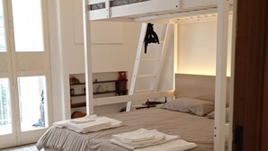 Ein Schlafzimmer mit einem Etagenbett, einer Himmelsleiter, einem kleinen Regal und einer Tür, die auf einen Balkon führt.