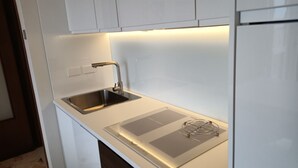 Eine moderne Küche mit Spüle aus Edelstahl, einem Einbauofen und einer weißen Arbeitsplatte.