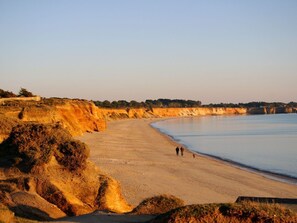 Uma praia costeira com areal arenoso e falésias.